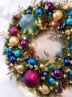 A decadent wreath of colourful abundance with rich golds, deep turquoise, royal purples and touches of flamboyant pinks. A real warm welcome home for anyone.